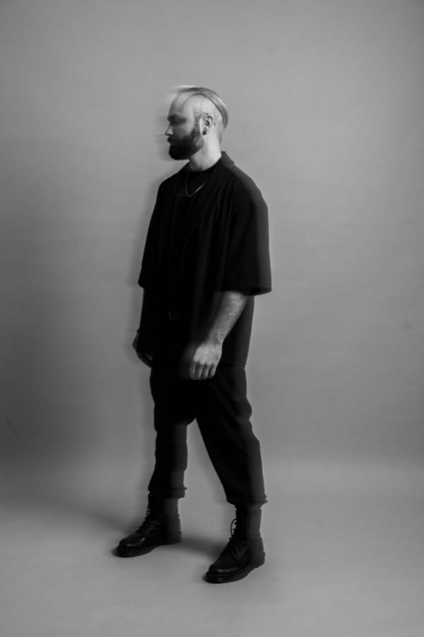 Sandro of One Lunar Day, photographed in black against a pale studio wall.